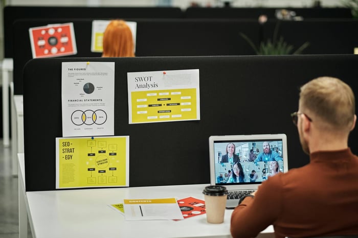 Business meeting over video call in modern office with charts and documents.